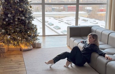 Barışçıl, şık, orta yaşlı, beyaz kadın dalgın, rüya gibi bir yüz ifadesi takınıyor, gülümsüyor, Noel arifesini kutluyor. Yüksek kalite fotoğraf