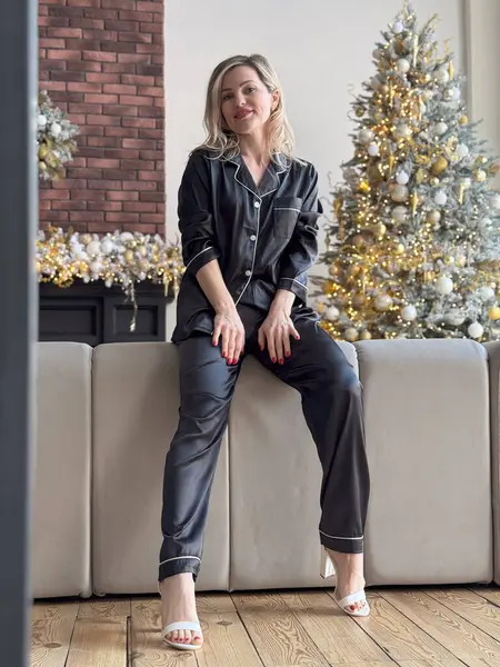 Siyah pijamalı sarışın kadın Noel ağacının yanında poz veriyor. Yüksek kalite fotoğraf