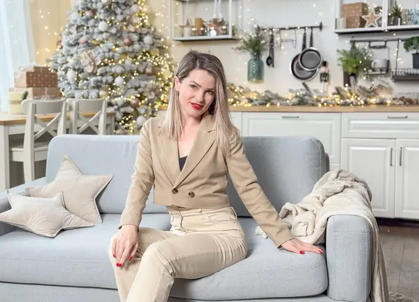 Güzel genç bir kadın Noel günü evde dinleniyor, Noel ağacının yanında kanepede oturuyor. Yüksek kalite fotoğraf