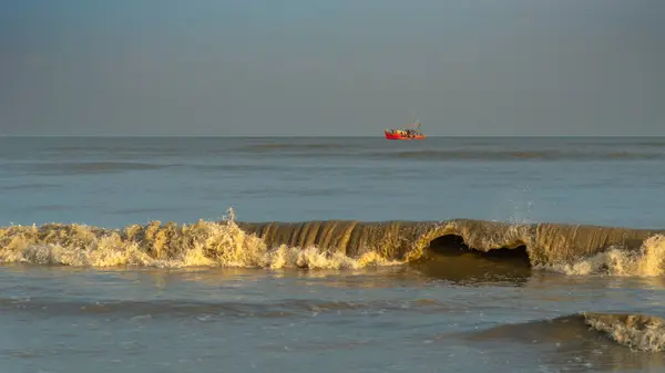 stock image October 24,2023. Orissa,India. Landscape View of Tidal Waves Overlooking a Wooden Fishing Boat.