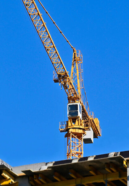 Tower crane and construction against blue sky