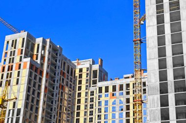 Vinçli ve mavi gökyüzü olan yüksek katlı bir inşaat alanı