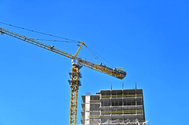 Vinçli ve mavi gökyüzü olan çok katlı bir inşaat alanı.