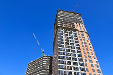 Vinçli ve mavi gökyüzü olan çok katlı bir inşaat alanı.