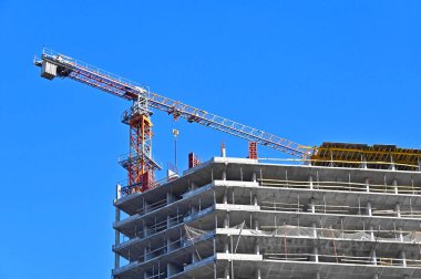 Vinçli ve mavi gökyüzü olan çok aşamalı inşaat alanı