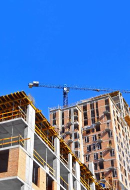 Vinçli ve mavi gökyüzü olan çok aşamalı inşaat alanı