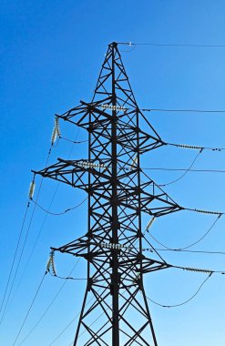 Mavi gökyüzü arkaplanı üzerinde yüksek voltaj iletim hattı