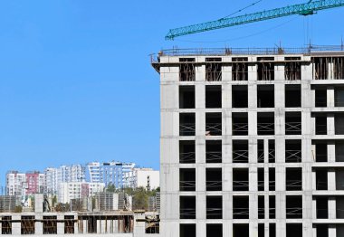 Vinçli ve mavi gökyüzü olan çok katlı bir inşaat alanı.