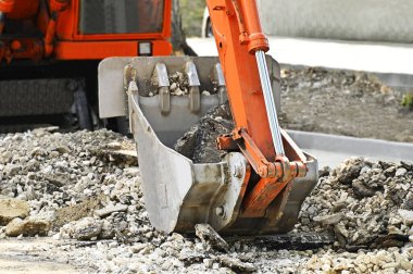 Yol yapımında paslı kazıcı kepçesi ve bozuk asfalt