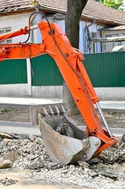 Yol yapımında paslı kazıcı kepçesi ve bozuk asfalt