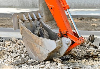 Yol yapımında paslı kazıcı kepçesi ve bozuk asfalt