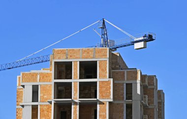 Vinçli ve mavi gökyüzü olan çok katlı bir inşaat alanı.