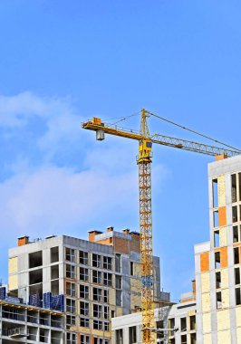 Mavi gökyüzüne karşı vinç ve yüksek bina inşaatı