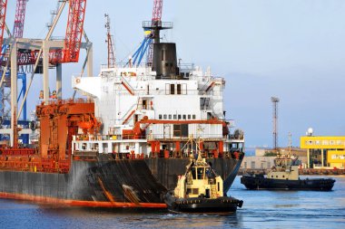 Odessa, Ukrayna 'daki rıhtıma giden büyük bir kargo gemisine yardım eden römorkör.