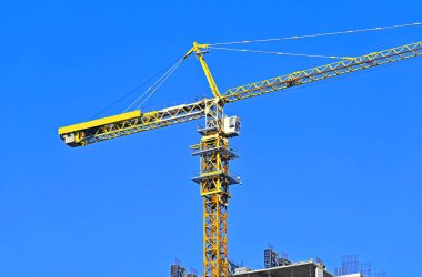 Mavi gökyüzüne karşı yüksek inşaat kulesi vinci