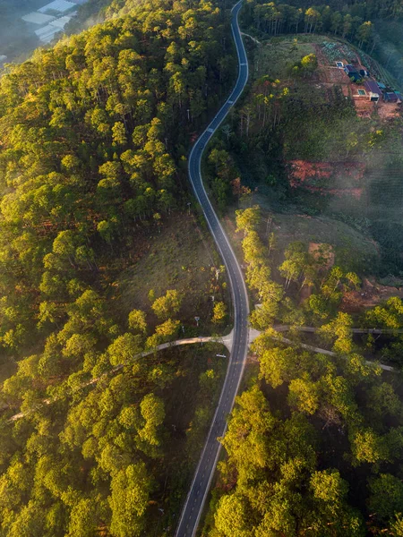 Winding road from high mountain pass, in spring time. Aerial view by drone
