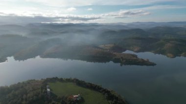 Göl kenarındaki küçük adanın turkuaz, kristal berrak suyla çekilmiş insansız hava aracı görüntüsü. Dai Ninh Gölü, Vietnam