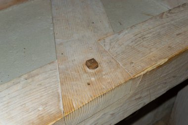 Mimari bir çerçevedeki ahşap kiriş yapısının ayrıntılı görüntüsü, bir inşaat projesinde işçiliği ve karmaşık ahşap işçiliğini gözler önüne seriyor