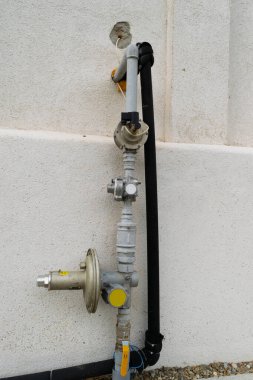 Elektrik idaresi için kullanılan beton bir duvara bağlı boruları ve vanaları olan bir dış gaz sayacına yakın plan.