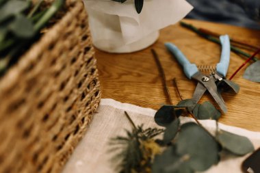 Bir çiçekçinin yaratıcı alanına yakın çekim. Bitkileri budamak, yaprakları kesmek ve hasır sepet yapmak için kullanılıyor.