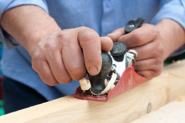 Bir uçakla ahşabı düzleştirmek, marangozun ellerine yakın çekim