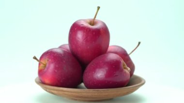 Beyaz zemin üzerinde ahşap plaka içinde kırmızı olgun organik küçük elma yan görüş yığını.