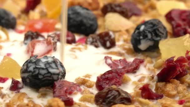 将牛奶倒入盛有甜干热带水果 葡萄干 桑树和菠萝的有机脆谷类早餐中 — 图库视频影像