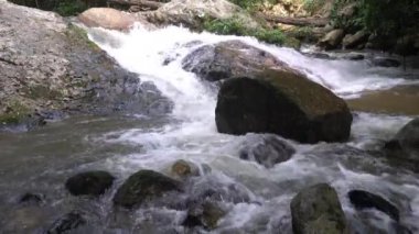 Wild clear natural mountain water flowing down through the rocks in the tropical rainforest of Thailand.