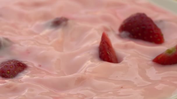 イチゴヨーグルトの回転に落ちる新鮮な熟したイチゴの高い角度のビューの作品 — ストック動画