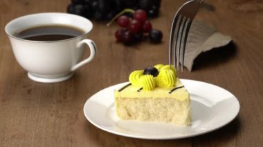 Taking a piece of delicious homemade sponge cake in white ceramic plate with a cup of hot black coffee and ripe organic seedless grapes for breakfast.