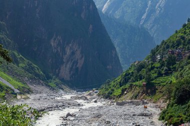 Ağır ekipmanlarla vadideki nehir manzarası ve Uttarakhand, Hindistan 'daki yeşil himalaya dağında küçük bir köy..