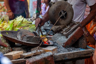 Hintli adam mısır kızartıyor, Hint sokak yemekleri sokak pazarında hava üfleyici ve mısır koçanı yığınıyla, Rishikesh, Hindistan