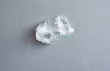 Beyaz arka planda baloncuklu kozmetik jel lekesi. Nemlendirici jel damlaları beyaz zemine damlıyor..