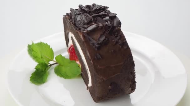 用巧克力片和绿色薄荷叶装饰的美味自制巧克力卷饼在白色背景的白色陶瓷盘中旋转 — 图库视频影像