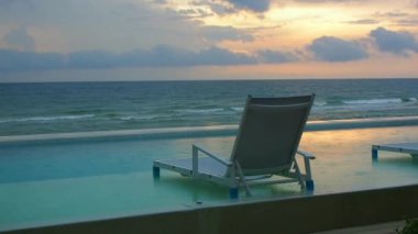 Sabahın ilk ışıklarıyla deniz kenarında yüzme havuzunda plaj sandalyesinin görüntüsü baş döndürücü..