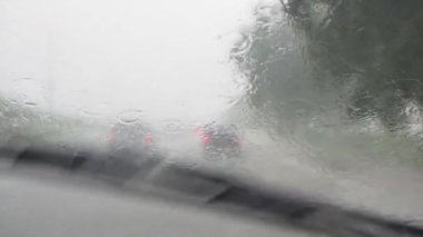 Şiddetli yağmurda çalışan arabanın ön camından bak. Silecek ön camı temizliyor. Şiddetli yağmur mevsiminde karayolunda trafik.