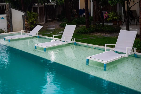 View row of white beach chairs in swimming pool in a resort villa at Hua Hin sea beach.