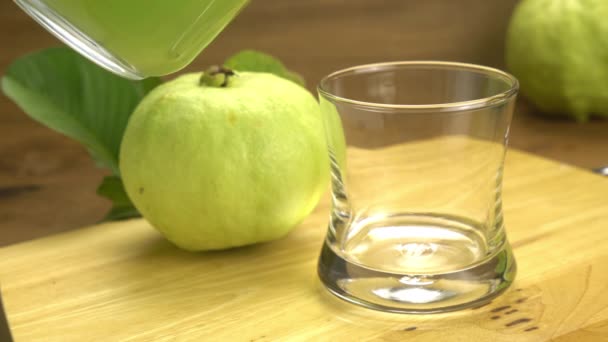 Ρίχνουμε Βιολογικό Χυμό Γκουάβα Διάφανο Ποτήρι Ώριμα Φρούτα Γκουάβα Ξύλινη — Αρχείο Βίντεο