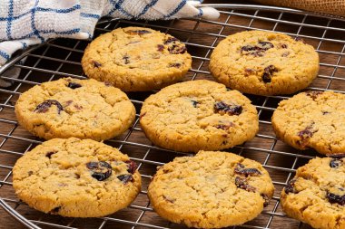 Yüksek açılı ev yapımı yulaf gevreği ve ahşap masadaki metal soğutma rafında kızılcık bisküvileri..