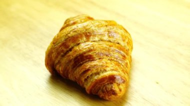 Yakın çekimde taze pişmiş lezzetli ev yapımı Fransız kruvasanı ahşap tahtada dönüyor..