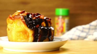 Kuru üzümlü çöreğin üzerine serpiştirilmiş gökkuşağı parçacıkları serpiştirilmiş fındık ve beyaz seramik tabakla süslenmiş çikolata..