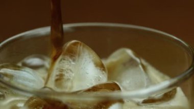 Şeffaf bardağa kola döken yakın görüntü. Buzlu kola bardağında hava kabarcıkları..