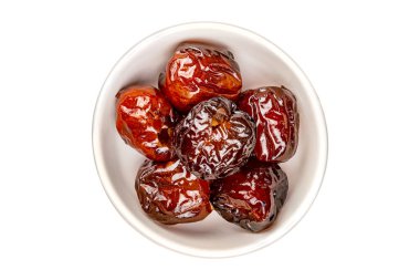 Beyaz arka planda izole edilmiş beyaz seramik kasede şerbete sarılı tatlı çin jujube meyvesi yığını.