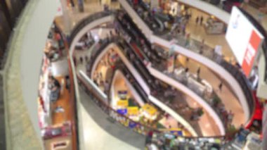 Modern bir alışveriş merkezinde yürüyen ve alışveriş yapan bulanık ve tanınamaz haldeki kalabalığın iç mekanı.