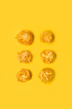 Kuru erişteler sarı arka planda izole edilmiş ve kopyalama alanı var.