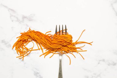 Kırmızı biberli spagetti ve mermer mutfak tezgahında çatal.