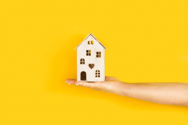 Vrouw Hand Met Een Wit Houten Speelgoedhuis Een Gele Achtergrond — Stockfoto
