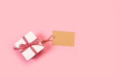 Kırmızı ve beyaz kareli bir kutu ve pembe arka planda boş bir etiket.