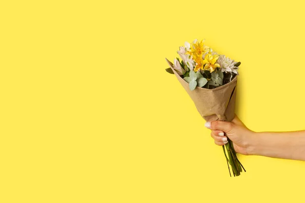 stock image Woman hand holding a yellow and white flowers bouquet on a yellow background with copy space