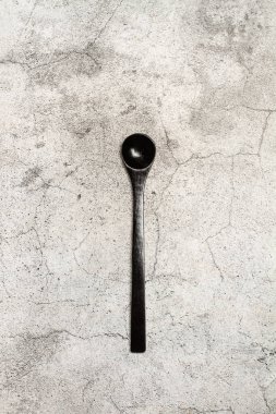 A black spoon on a gray stone kitchen counter background with copy space